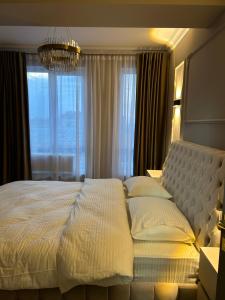 a bedroom with a large white bed with a chandelier at GT apartments in Chisinau in Chişinău