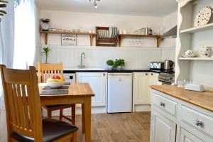 a kitchen with white cabinets and a wooden table at Althea House with parking in Padstow