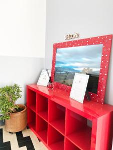 a red dresser with a mirror and a plant at EASYROOMS ONE in Parma