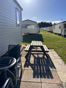 - une table de pique-nique et des chaises à côté d'un bâtiment dans l'établissement Family Caravan, Seton sands, Haven holiday village, à Port Seton
