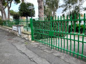 ein grüner Zaun mit einer Bank neben einer Straße in der Unterkunft Fronte Mare Villa Acquasanta zona "LA FIUMETTA" Terracina in Terracina