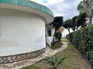 einen seitlichen Blick auf ein Haus mit einer Wand und einem Gehweg in der Unterkunft Fronte Mare Villa Acquasanta zona "LA FIUMETTA" Terracina in Terracina