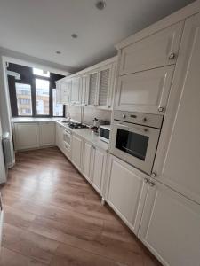 a kitchen with white cabinets and a wooden floor at Apartament in Botosani in Botoşani