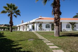 a white house with palm trees in front of it at Quinta Flamingos - Live, Work, Play in Corroios