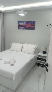 een witte slaapkamer met een wit bed en een schilderij bij Λαμπερό Διαμέρισμα 1 in Thessaloniki