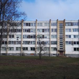 um prédio de apartamentos com uma árvore em frente em Mini apart Žvėrynas em Vilnius