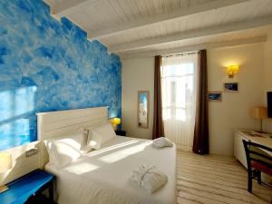 a bedroom with a white bed and a blue wall at Hotel La Villa Del Mare in Cagliari