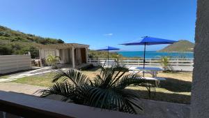 a patio with tables and umbrellas and the ocean at Lydia`s View in Canouan