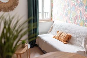 un letto con un cuscino in una stanza con una finestra di Le Tropical : T2 rénové Ambiance Cosy et Colorée a Mazamet