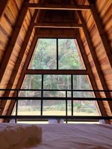 - une grande fenêtre dans une chambre avec un lit dans l'établissement Hotel Nativa Eco, à Mandirituba