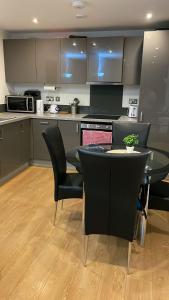 eine Küche mit einem Tisch, schwarzen Stühlen und einer Theke in der Unterkunft YES Apartments in Crayford
