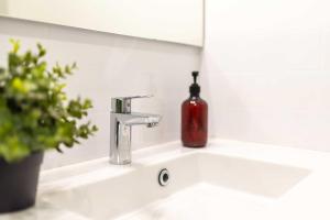 un lavandino in bagno con una bottiglia di sapone rosso di Le Tropical : T2 rénové Ambiance Cosy et Colorée a Mazamet