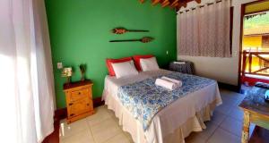 a bedroom with a bed with a green wall at Thai Pousada in Ubatuba