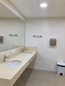 baño con 2 lavabos y espejo grande en Vive la experiencia de dormir acunado por las olas cerca de Barcelona en Castelldefels