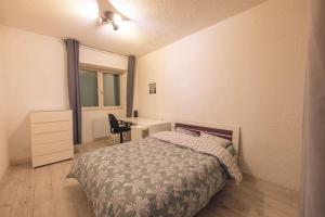 1 dormitorio con cama, escritorio y ventana en Tanière urbaine, en Lons-le-Saunier