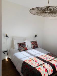 ein weißes Bett mit Kissen in einem weißen Schlafzimmer in der Unterkunft Les Terrasses des Antiques 2 in Saint-Rémy-de-Provence