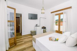 a white bedroom with a bed and a television at Kissamos Bay Hotel in Kissamos