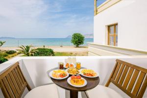 a table with food on a balcony with the ocean at Kissamos Bay Hotel in Kissamos