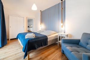 ヤスタルニャにあるApartamenty Białe Piaskiのベッドルーム(ベッド1台、青いソファ付)