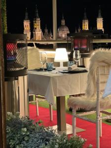 サラゴサにあるアパートホテル ロス ヒラソレスのワイングラスとランプが付いたテーブル
