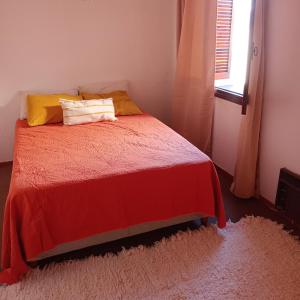 1 dormitorio con 1 cama con manta roja y ventana en Departamento"la casa de catita "la pampa general pico en General Pico