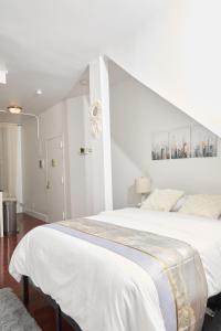 a white bedroom with a large white bed with an attic at Private Loft in Hells Kitchen near Times Square in New York