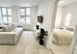 グダニスクにあるGdansk Apartmentsの白いリビングルーム(ソファ、ベッド付)