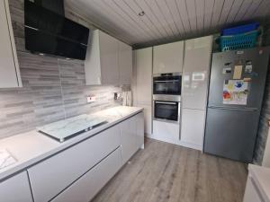uma cozinha com armários brancos e um frigorífico em Spacious 3bed semi/Gamesroom/Drive/10mins to City em Wrexham