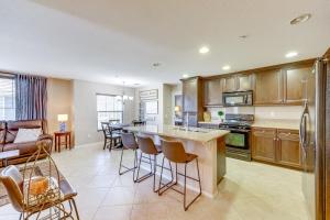 a kitchen with wooden cabinets and a kitchen island with bar stools at Oxnard Vacation Rental about 2 Mi to Beach! in Oxnard
