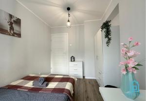 a bedroom with a bed and a vase with pink flowers at Lovely Room in Gdańsk