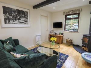un soggiorno con divano verde e tavolo in vetro di Corner Cottage a Troutbeck