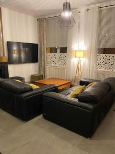 a living room with two leather couches and a table at Family cottage 4 chambres in Bourbourg