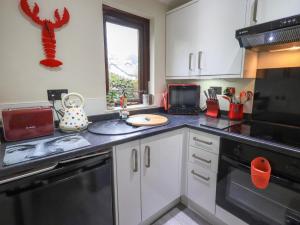 een keuken met witte kasten en een zwarte vaatwasser bij Corner Cottage in Troutbeck