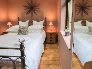a bedroom with two beds with white pillows at Corner Cottage in Troutbeck