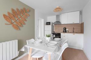 a kitchen with a white table and white chairs at Le Cottage in Mazamet