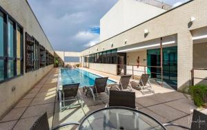 een patio met stoelen en een zwembad in een gebouw bij Flat - Comfort Hotel - Taguatinga in Brasilia