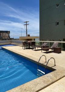 una piscina con mesa y sillas junto a un edificio en Novo quarto e sala - J. Armação - Vista Mar! en Salvador