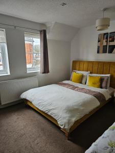 Un dormitorio con una cama con almohadas amarillas y una ventana en The Gungate, en Tamworth