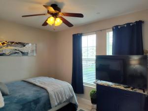 a bedroom with a ceiling fan and a flat screen tv at Buena Vista home in Visalia +16 photos