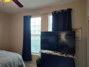TV de pantalla plana en un dormitorio con ventana en Buena Vista home, en Visalia