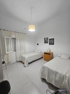 a white bedroom with two beds and a lamp at Casa LH en Villa María, Córdoba in Villa María