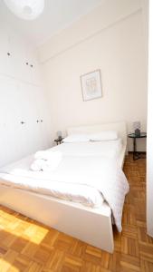 a white bed in a white room with a wooden floor at Cozy Apartment in Hermoupolis in Ermoupoli