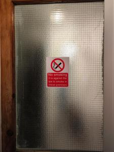una señal de no fumar en una puerta de cristal en Garden of peace, en Erith