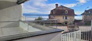 a balcony with a view of a house and the water at Studio Avant-Scène in Neuchâtel
