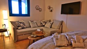 a living room with a couch and a flat screen tv at The Olive Tree in Ancient Epidauros