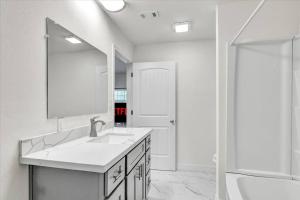 a white bathroom with a sink and a mirror at Stylishly Remodeled 2-Bedroom home in Orangefield in Orange +9 photos