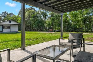 a patio with a glass table and chairs and a field at Stylishly Remodeled 2-Bedroom home in Orangefield in Orange