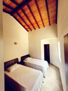 um quarto com 2 camas e um tecto de madeira em HACIENDA EL ENSUEÑO em Floridablanca