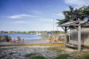 ein Holzsteg mit Stühlen und ein Pavillon neben dem Wasser in der Unterkunft Bluff Shoal Motel in Ocracoke