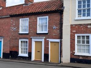 a brick building with two yellow doors on a street at Luxury family and dog friendly cottage in North Norfolk, Aylsham in Aylsham